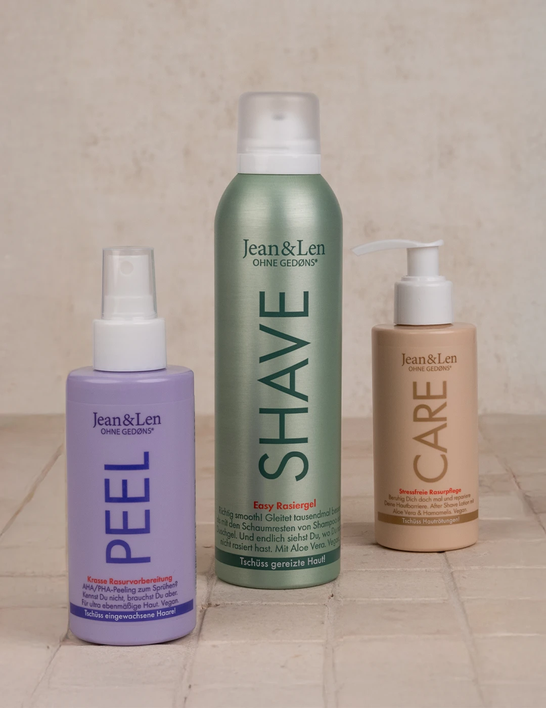 Aftershave, Rasierschaum und Intimpeeling vor neutralem Steinhintergrund