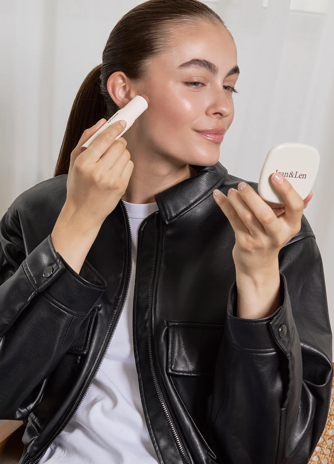 Cremefarbener Make-up-Stick und Jean&Len Taschenspiegel, Model trägt den Stick auf die Wange auf