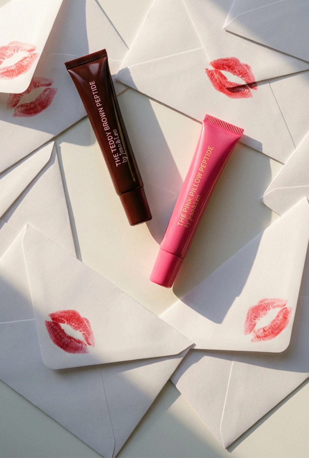 Lip Treatments Teddy Brown und Pink Pillow umgeben von Liebesbriefen mit Kuss-Abdrücken darauf.