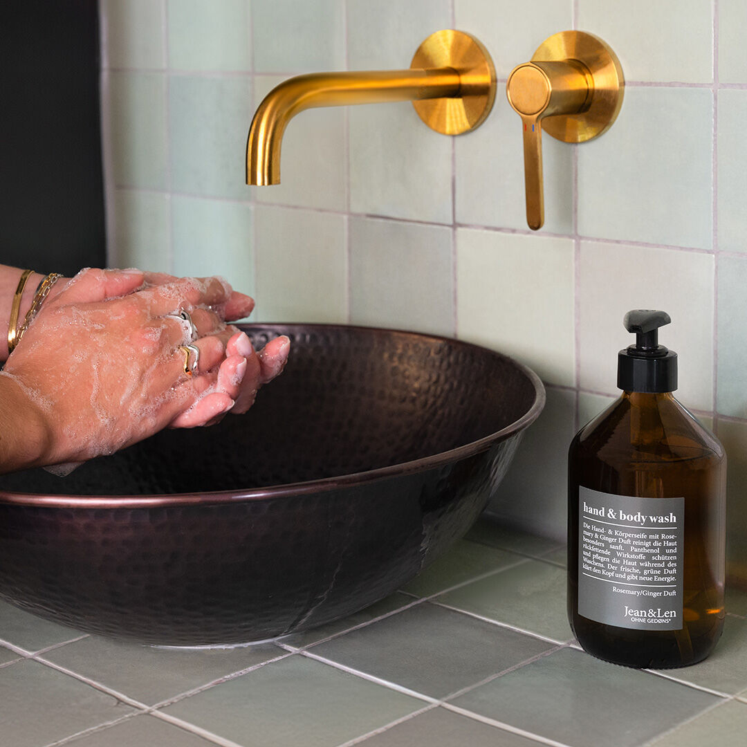 Gründliche Handreinigung mit Jean&Len Hand & Body Wash – stilvoll und pflegend Person wäscht sich die Hände mit Jean&Len Hand & Body Wash an einem goldenen Wasserhahn