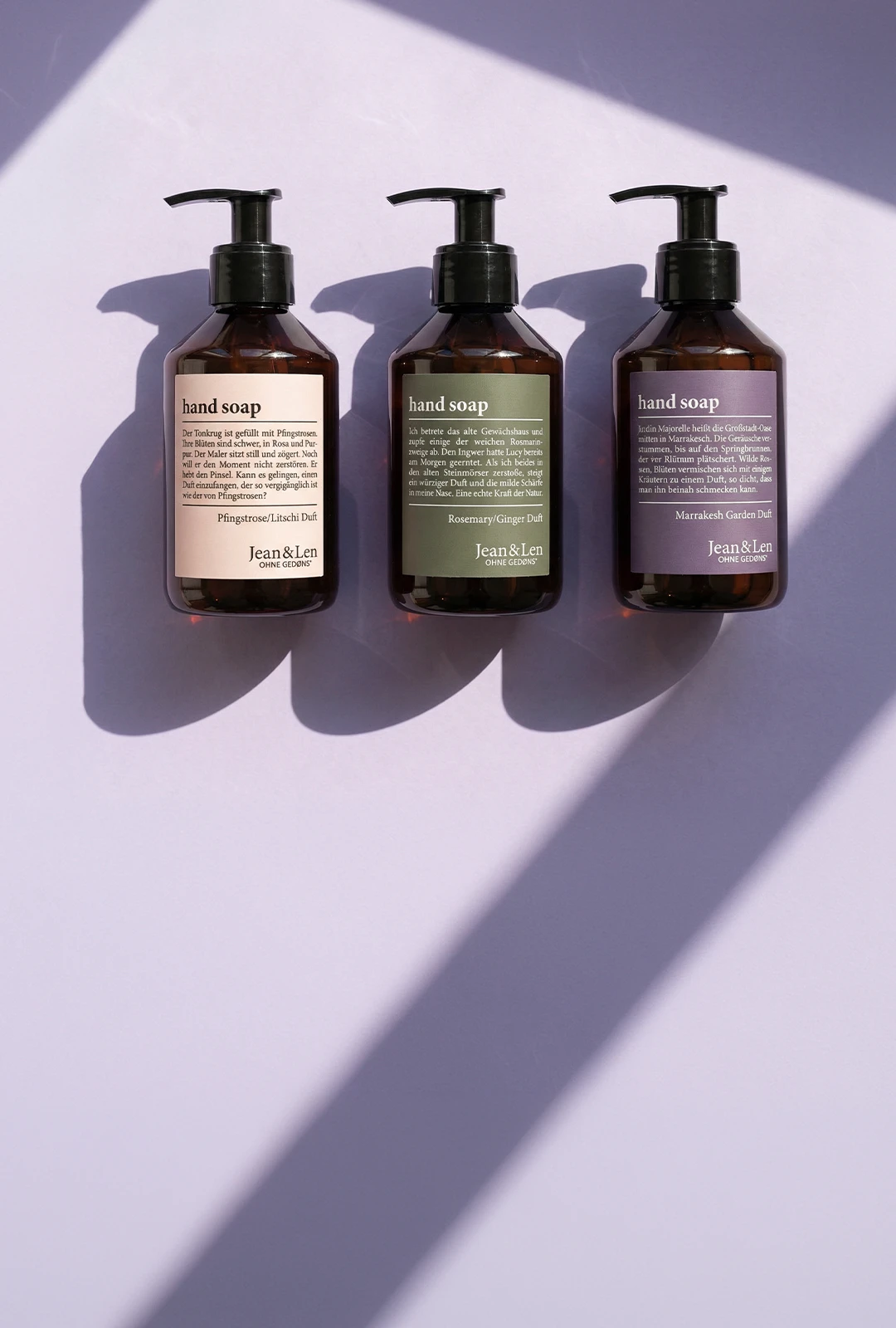 Drei Jean&Len Handseifen in braunen Pumpspendern mit unterschiedlichen Duftvarianten auf hellem Hintergrund im Sonnenlicht.