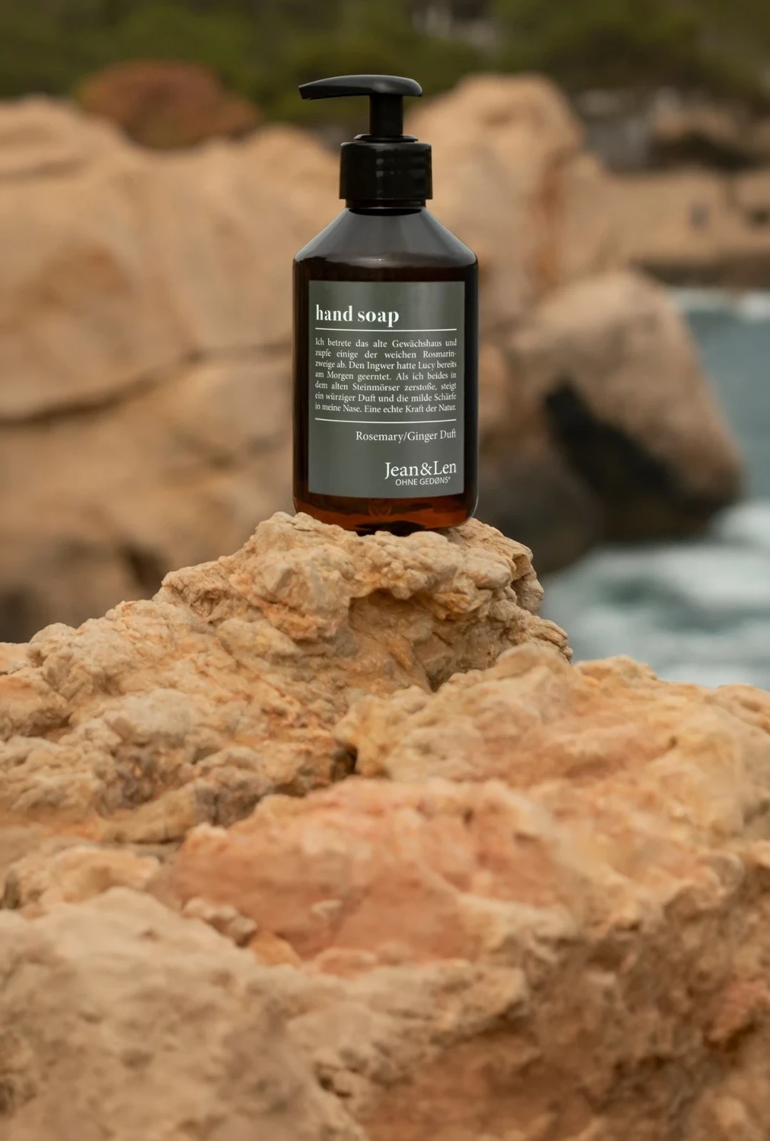 Jean&Len Handseife Rosemary/Ginger, braune Pumpflasche auf Felsen am Meer