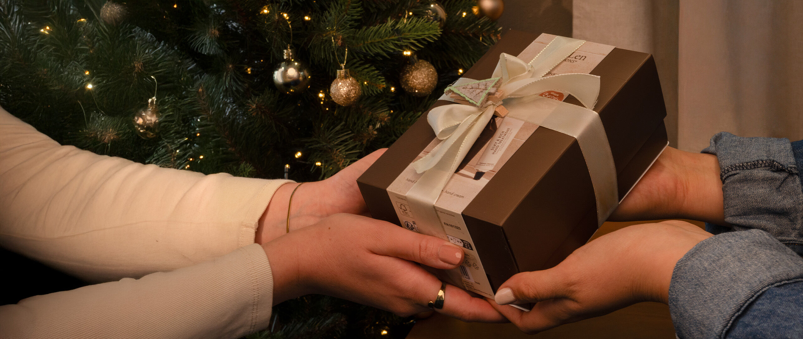 Handseife und Handbalm Rosemary/Ginger in einer braunen Pumpflasche stehen auf einem Holztablett in einem weißen Steinbad. Daneben sind ein Steinwaschbecken und ein grünes Handtuch zu sehen.