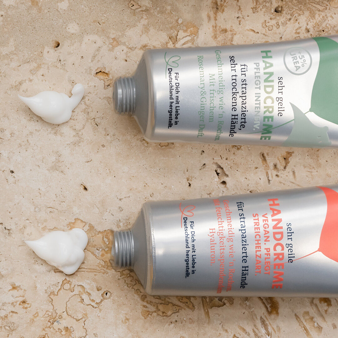 Intensive Handpflege von Jean&Len – vegane Cremes für strapazierte Hände Zwei Jean&Len Handcremes in Alutuben mit Creme-Spuren auf Naturstein-Oberfläche
