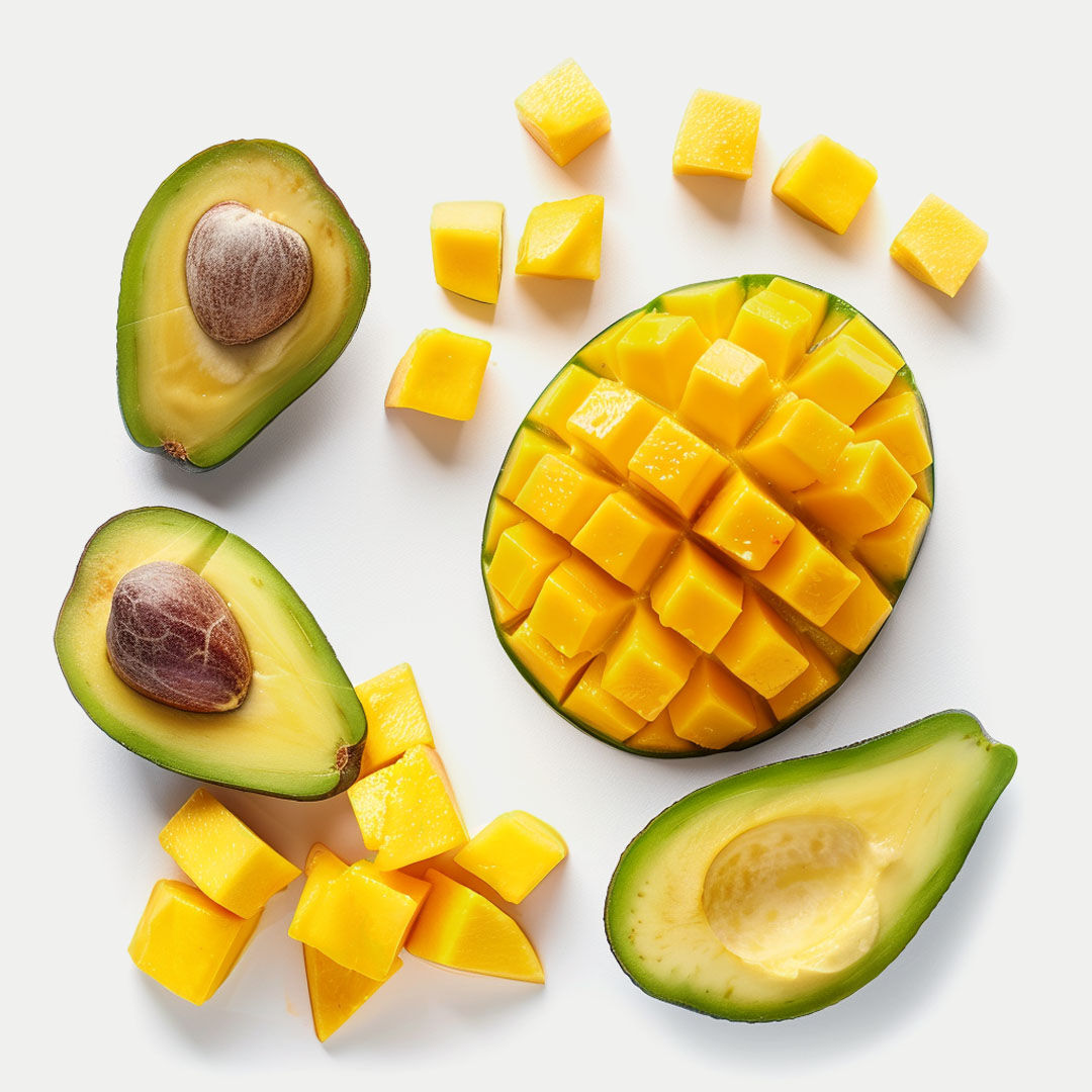 Aufgeschnittene Avocados und Mangostücke auf hellem Untergrund.