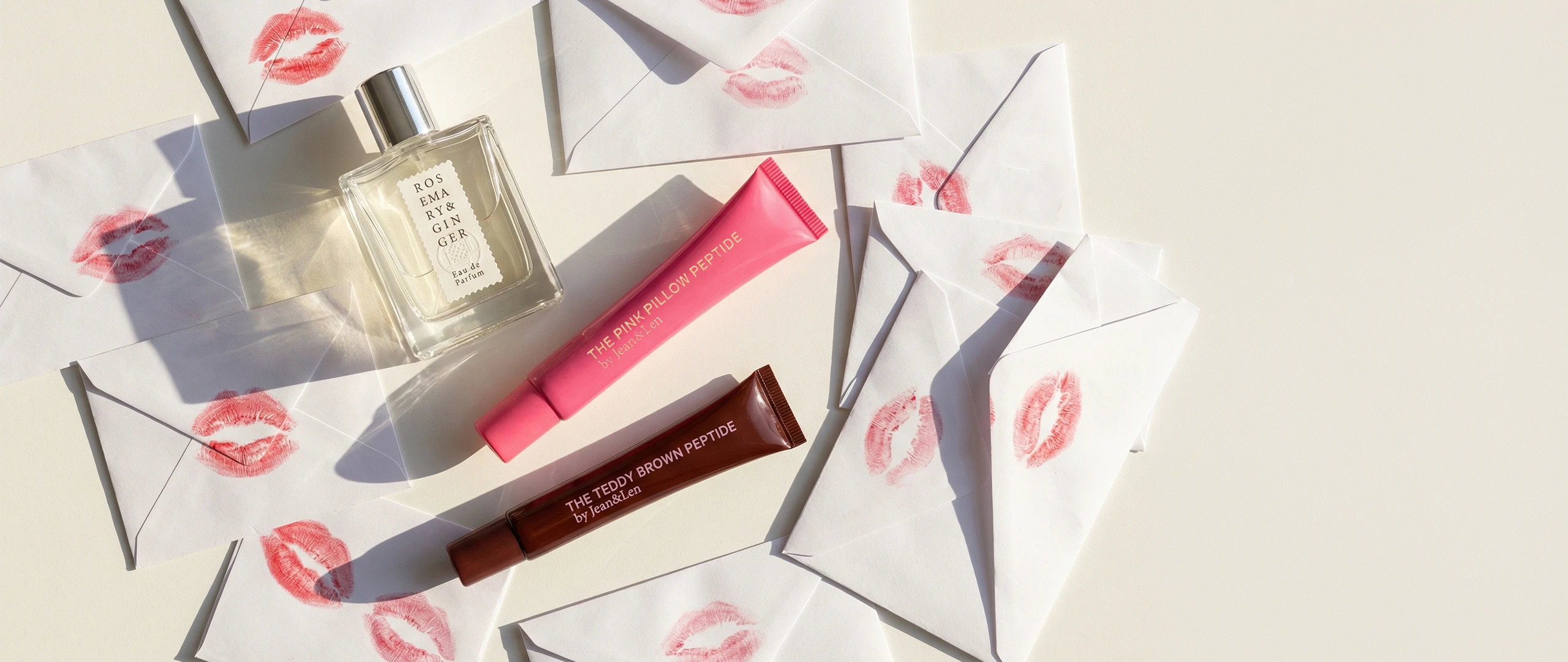 Lip Treatments Teddy Brown und Pink Pillow umgeben von Liebesbriefen mit Kuss-Abdrücken darauf.