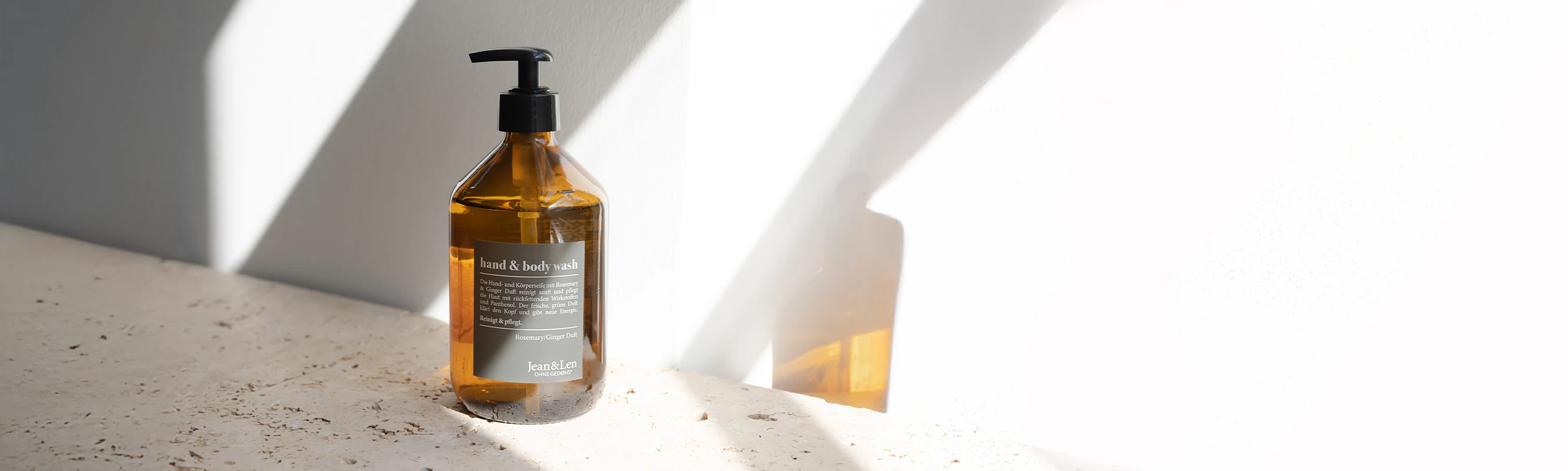 Vegane Körperpflege mit Rosemary & Ginger – stilvoll, pflegend und ohne Gedøns Jean&Len Hand & Body Wash Rosemary/Ginger in 500 ml Glasflasche vor weißer, sonnenbelichteter Wand