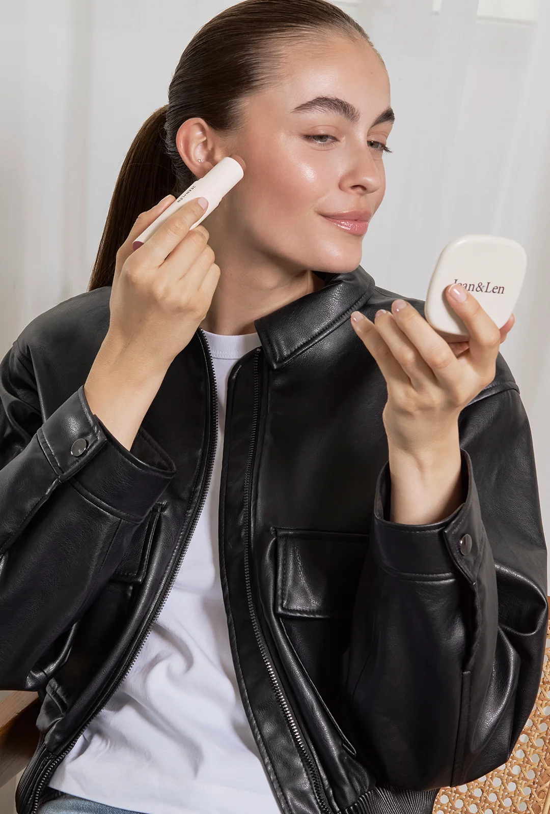 Cremefarbener Make-up-Stick und Jean&Len Taschenspiegel, Model trägt den Stick auf die Wange auf
