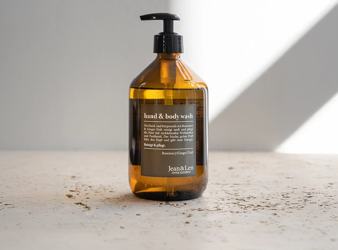 Vegane Körperpflege mit Rosemary & Ginger – stilvoll, pflegend und ohne Gedøns Jean&Len Hand & Body Wash Rosemary/Ginger in 500 ml Glasflasche vor weißer, sonnenbelichteter Wand