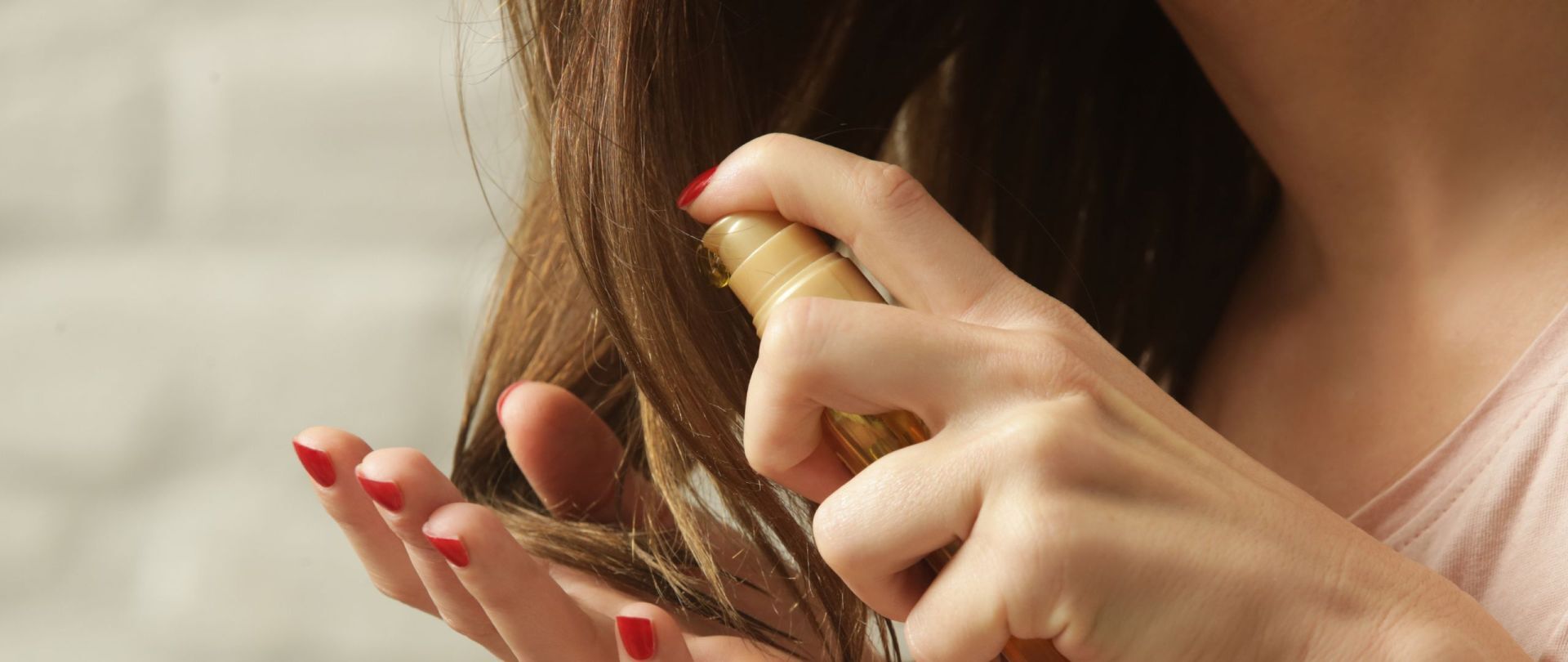 Frau ölt trockene Haarspitzen mit Pflegeöl ein.